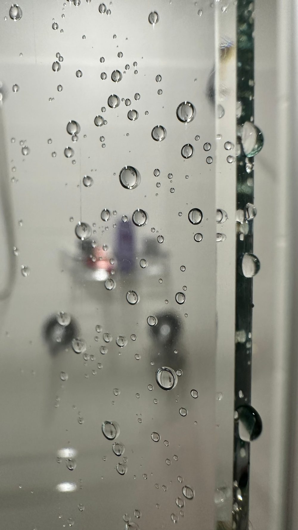 Water beading into round droplets on the hydrophobic-coated shower glass